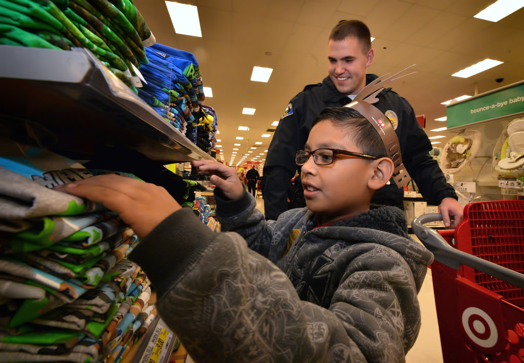 With the help of Anaheim PD Officer Jared DeWald behind him, Jonathan Sandoval, 10, take advantage of Anaheim PDÕs Shop With a Cop to look for clothes for himself and his family. Photo by Steven Georges/Behind the Badge OC