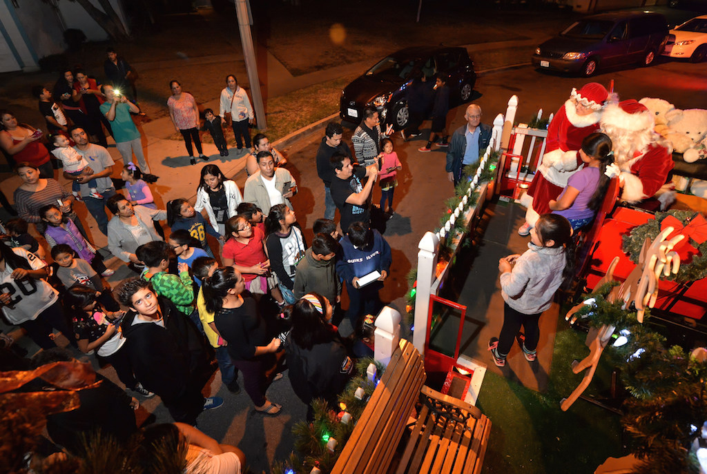 Kids and parents waiting at the corner of Scherer Place and Del Amo Avenue in Tustin greet Mr. and Mrs. Claus as Santa's Sleigh arrives in their neighborhood. Photo by Steven Georges/Behind the Badge OC