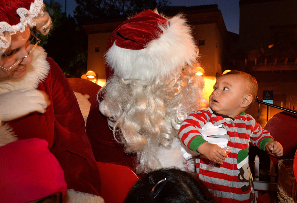 One-year-old Vincent Luna of Tustin doesn’t quite know what to make of the big guy with the white beard as Mr. and Mrs. Claus tour Tustin. Photo by Steven Georges/Behind the Badge OC