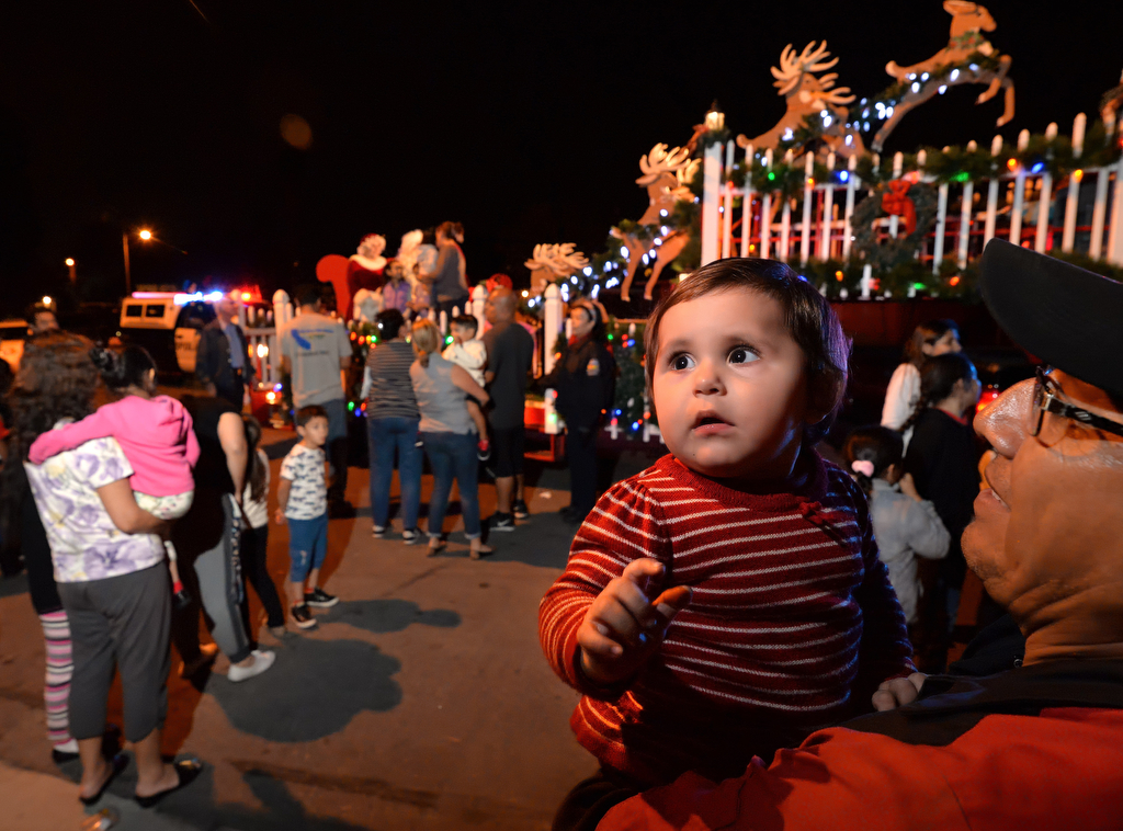 One-year-old Sofia is held by her grandfather as they wait their turn to visit Santa at the corner of Scherer Place and Del Amo Avenue in Tustin. Photo by Steven Georges/Behind the Badge OC
