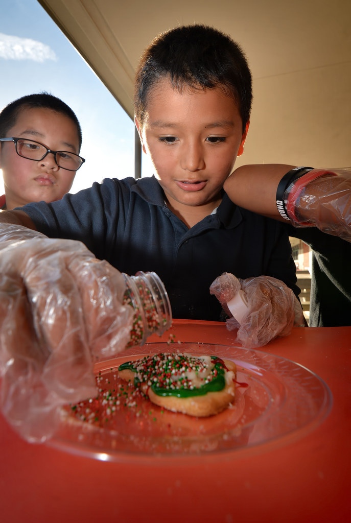 Adrian Eina, 8, adds a few sprinkles to cookies kids from Post Elementary School are decorating for the Garden Grove PD, part of a Boys & Girls Club of Garden Grove project. Photo by Steven Georges/Behind the Badge OC