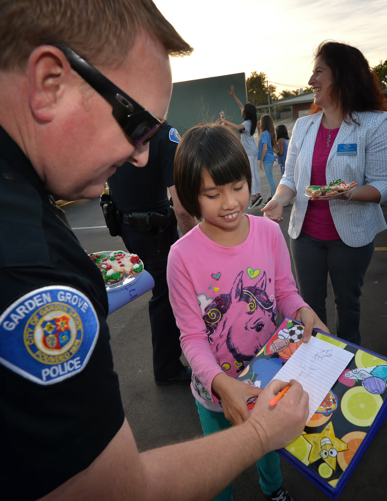 Kimberly Nguyen, 9, of Post Elementary School, asks for the autograph of Garden Grove PD Officer Jason Fulton during a visit to the school. Photo by Steven Georges/Behind the Badge OC
