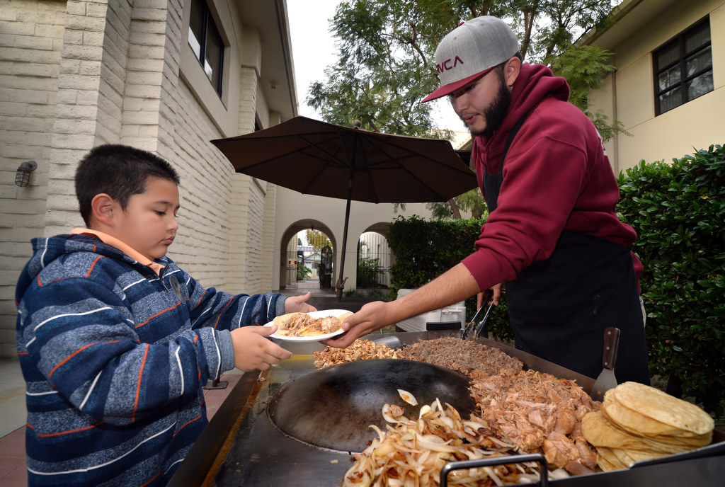 Randy Rouse, 8, gets a meal served to him by Salvador Valadez of Tacos Tacos A Domicilio, at Fullerton Police Headquarters before heading out to Target for Fullerton PD’s Shop With a Cop. Photo by Steven Georges/Behind the Badge OC