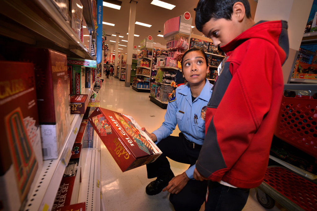 Victoria Rangel, parking control for the Fullerton PD, helps Nathan Vaughn, 10, pick out a game box that includes a chess set during Fullerton PD’s Shop With a Cop. Photo by Steven Georges/Behind the Badge OC