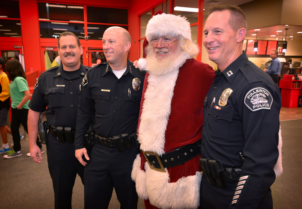 Capt. Scott Rudisil, left, Police Chief Dan Hughes and Capt. John Siko pose with Santa during Fullerton PD’s Shop With a Cop event at the Target store in Fullerton. Photo by Steven Georges/Behind the Badge OC