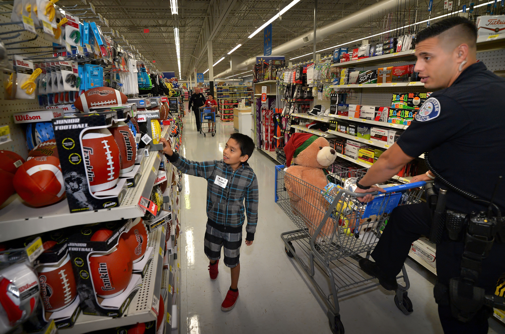 Nine-year-old Fernando Santana picks out a football with the help of Westminster PD Officer Mike Gradilla during Westminster PD’s annual Shop With a Cop event at the Walmart in Westminster. Photo by Steven Georges/Behind the Badge OC