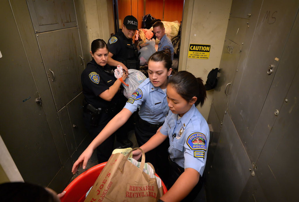 Fullerton Police Explorers Sgt. Mixtly Galarza and Lt. Tina Wu, right, help load donated clothes into the elevator in the basement of police headquarters to take to the drop off point for Clothes For The Cause, a fundraiser in part for 6-year-old Katherine King who suffers from an incurable brain stem tumor. Photo by Steven Georges/Behind the Badge OC