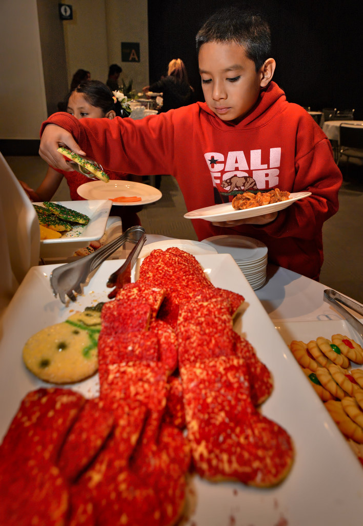 Christopher Cruz, 9, of Anaheim, adds a few Christmas cookies to his plate of food during the Burn Survivor’s Santa Jamboree at the Anaheim Convention Center. Photo by Steven Georges/Behind the Badge OC
