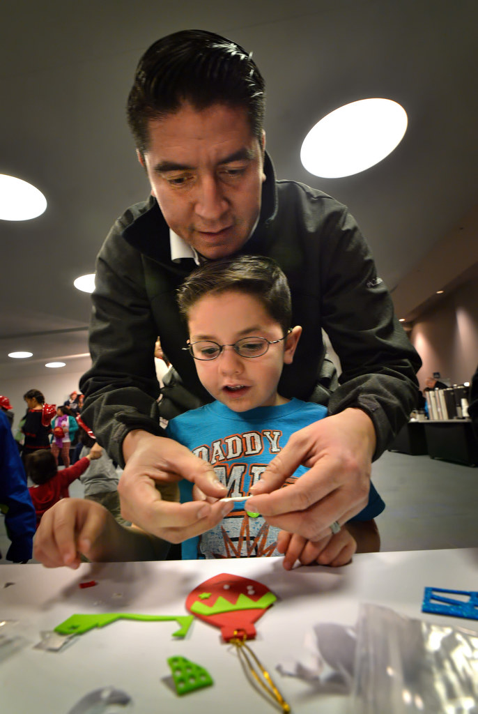 Jose Encino of La Habra works on Christmas crafts with his 5-year-old son, Andrew Encino, during the Burn Survivor’s Santa Jamboree at the Anaheim Convention Center put on by the UC Irvine Health Regional Burn Center and Anaheim Fire & Rescue. Photo by Steven Georges/Behind the Badge OC