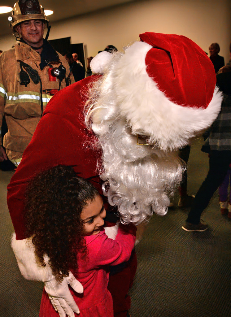 Santa gets hugs from kids who run up to him as he enters the Burn Survivor’s Santa Jamboree at the Anaheim Convention Center. Photo by Steven Georges/Behind the Badge OC