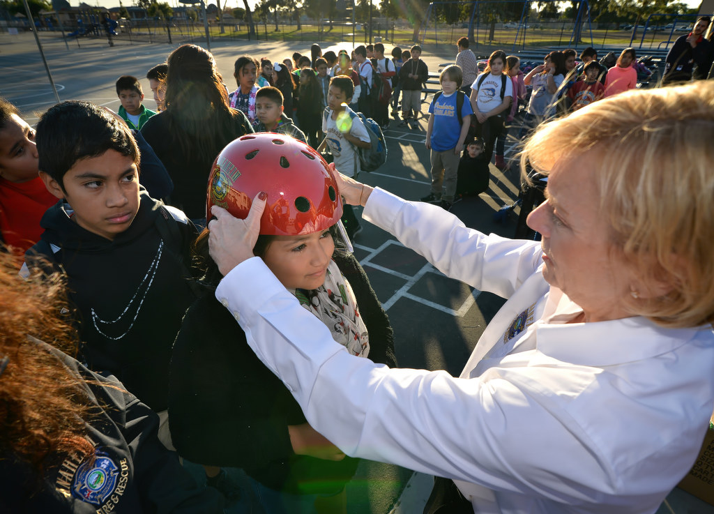 Amy Verdin, 11, is fitted for a new bicycle helmet by Marty DeSollar, external affairs manager for Anaheim Fire & Rescue, as other kids from Ponderosa Elementary School in Anaheim wait behind her for their helmet. The free helmet distribution is part of the Wear Your Helmet Like A Pro program. Photo by Steven Georges/Behind the Badge OC