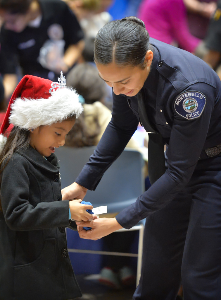 Police Recruit Frani Echavarria of Golden West College Police Academy, (sponsored by the Montebello PD) helps out Moco Guadalupe, 6, of Tustin with a beanbag toss game during Tustin PDÕs annual ÒSanta CopÓ at the Tustin Community Center. Photo by Steven Georges/Behind the Badge OC