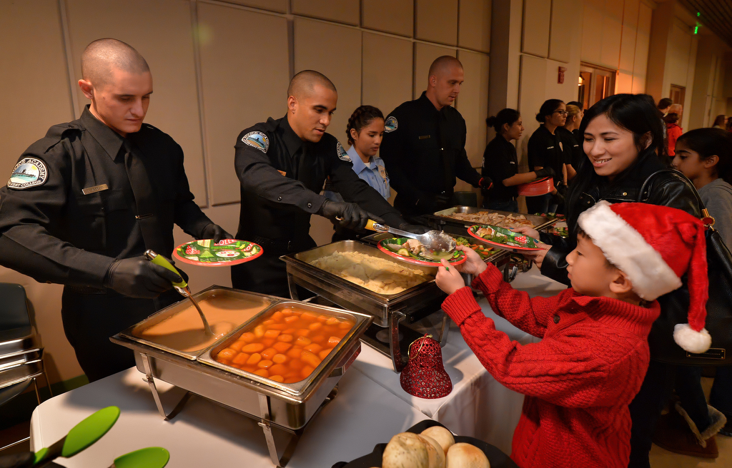 Seven-year-old Andy Trinh of Tustin and his mother Anna Trinh receive a Christmas dinner served by recruits from Golden West College Police Academy during Tustin PD’s annual “Santa Cop” at the Tustin Community Center. Photo by Steven Georges/Behind the Badge OC