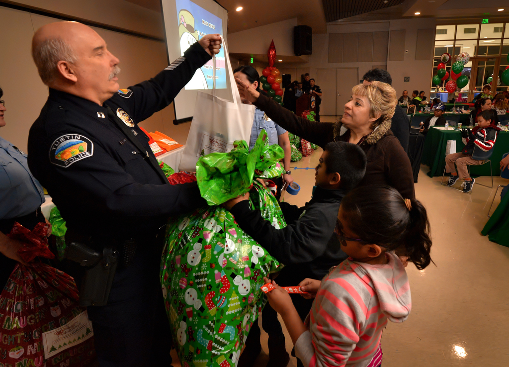 Tustin PD Capt. Steve Lewis hands Christmas gifts to the Carabarin family during Tustin PD’s annual “Santa Cop” at the Tustin Community Center. A set of gifts were handed out to each of the families that attended. Photo by Steven Georges/Behind the Badge OC