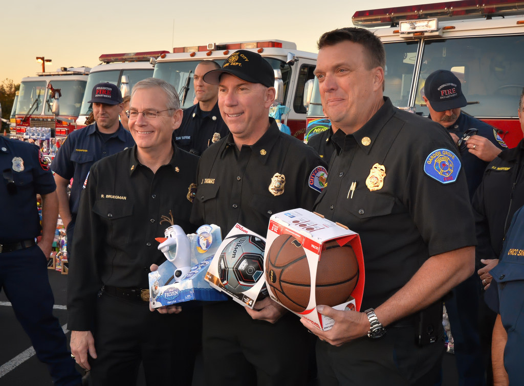 Anaheim Fire & Rescue Chief Randy Bruegman, left, City of Orange Fire Dept. Battalion Chief Jack Thomas and Garden Grove Fire Chief Tom Schultz during the Spark of Love Toy Drive at the Honda Center in Anaheim. Photo by Steven Georges/Behind the Badge OC