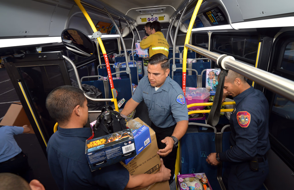 Garden Grove Firefighter N. Rodriguez, center, helps load one of the busses with toys during the "Stuff a Bus” Spark of Love Toy Drive at the Honda Center in Anaheim. Photo by Steven Georges/Behind the Badge OC