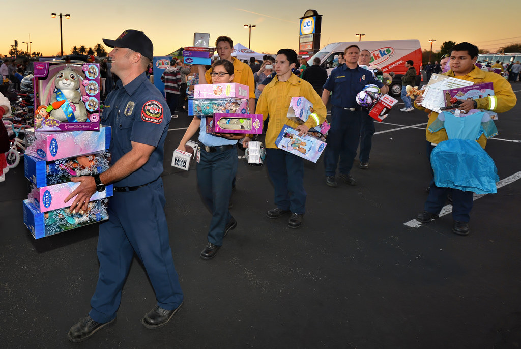 Firefighters carry toys to be loaded on busses during the "Stuff a Bus” Spark of Love Toy Drive at the Honda Center in Anaheim. Photo by Steven Georges/Behind the Badge OC