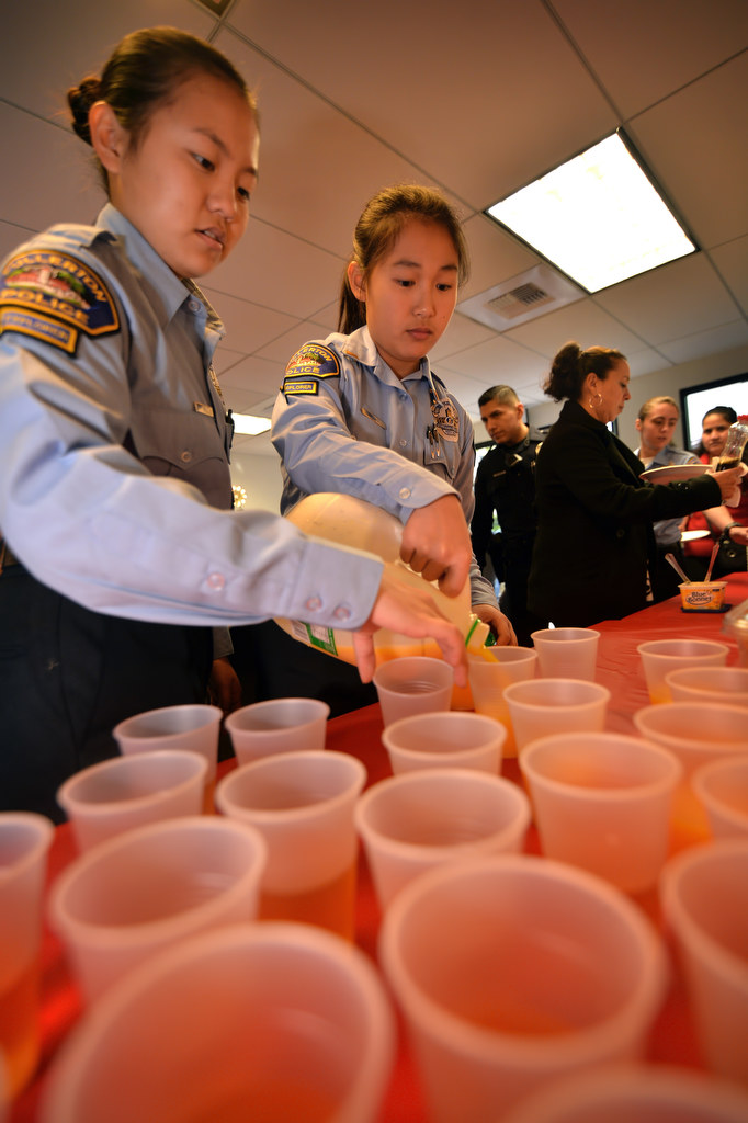 Fullerton Police Explorers Jessica Min, left, and Tina Wu pour the apple and orange juice drinks as the families arrive at police headquarters for breakfast, part of Fullerton PDÕs Adopt a Family program. Photo by Steven Georges/Behind the Badge OC