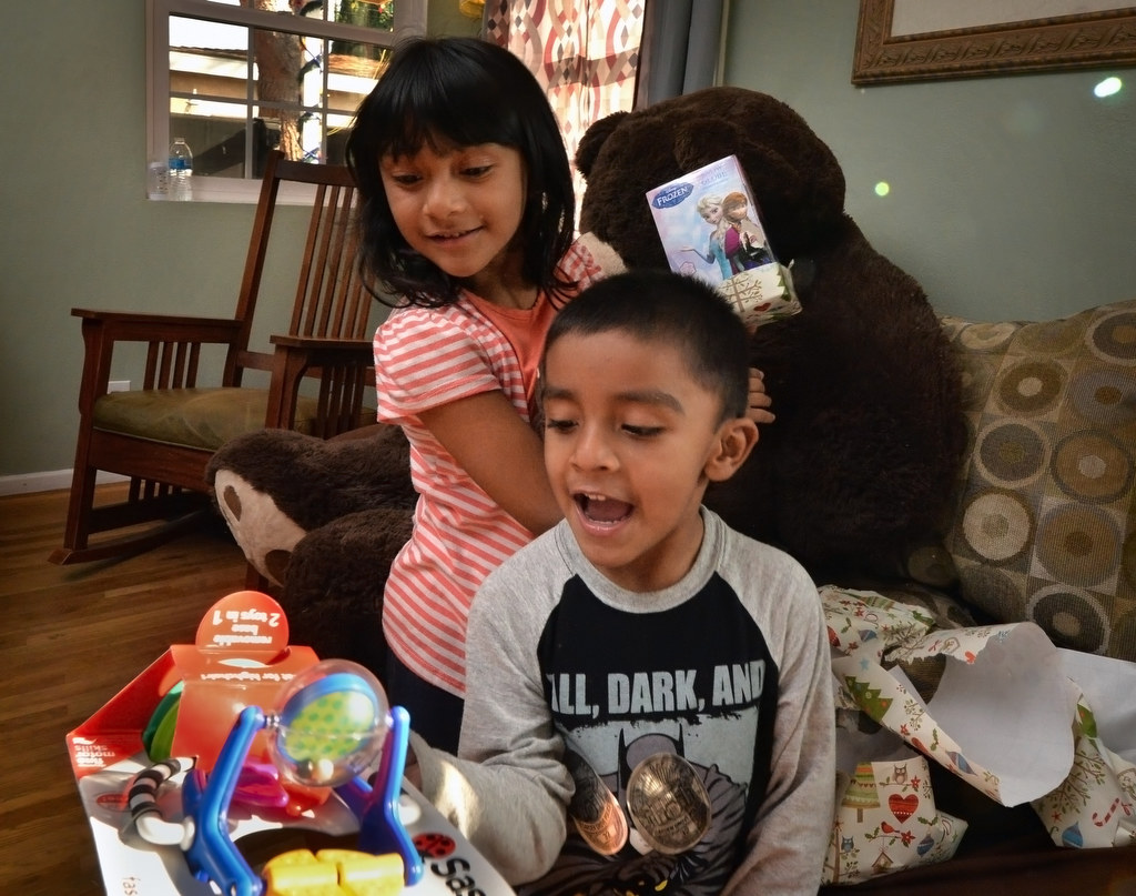 Emily Barragan, 5, looks over the shoulder of her brother Matthew Barragan, 3, after he unwrapped a Christmas present from the Garden Grove PD for his 3-week-old brother Gabriel. Photo by Steven Georges/Behind the Badge OC