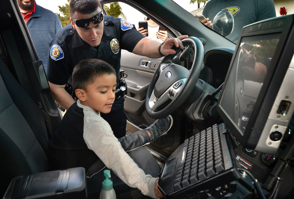 Matthew Barragan, 3, gets to flip the switch for the siren in the patrol car of Garden Grove PD Officer Mitchel Mosser. Photo by Steven Georges/Behind the Badge OC