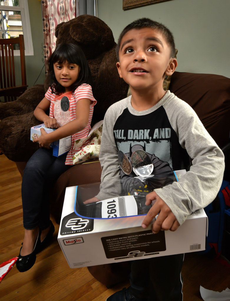 Three-year-old Matthew Barragan looks up at the Garden Grove PD officers after unwrapping a toy police car given to him by the GGPD. His sister, Emily Barragan, 5, is behind him also unwrapping Christmas presents. Photo by Steven Georges/Behind the Badge OC
