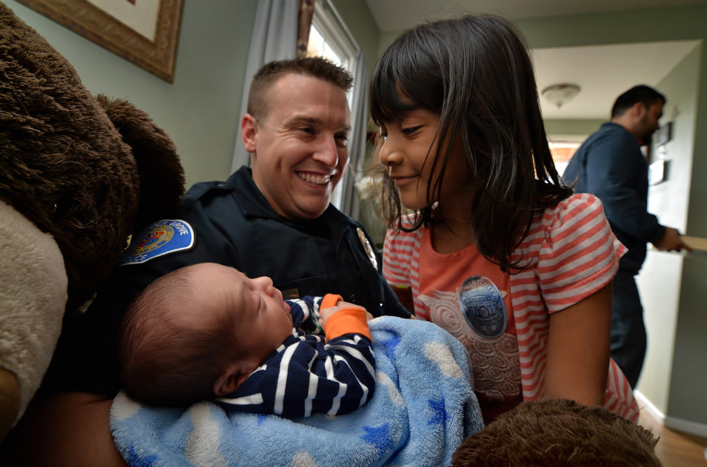Emily Barragan, 5, gets a close look at her 3-week-old brother Gabriel Barragan as he is held by Garden Grove PD Officer Mitchel Mosser. Garden Grove officers brought the Barragan family Christmas presents after their mother, Erika, passed away the day after giving birth to Gabriel. Photo by Steven Georges/Behind the Badge OC