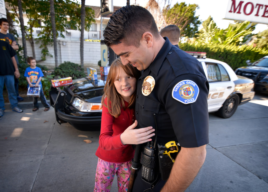 Melanie Born, 10, gives a thank you hug to Garden Grove Officer Ben Elizondo after he and other officers arrived at the Garden Grove Inn on Christmas day to hand out presents to kids less fortunate. Photo by Steven Georges/Behind the Badge OC