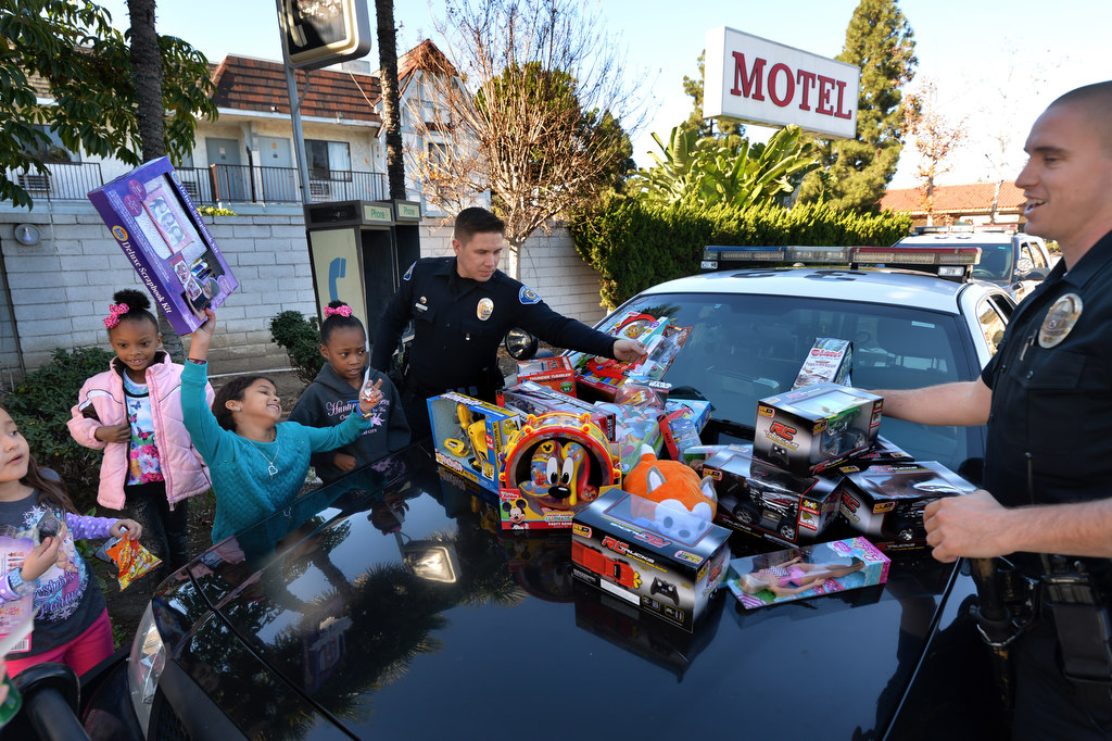 Nine-year-old Iris Hall smiles as she holds up her Christmas present that she received from Garden Grove PD officers Danny Mihalik and Gerald Jordan, right, as the officers arrived at the Garden Grove Inn to brighten up Christmas for children less fortunate. Other kids from left include IrisÕ sister Katie Hall, 7, Sun-Niya, 6, and Savanna, 9. Photo by Steven Georges/Behind the Badge OC