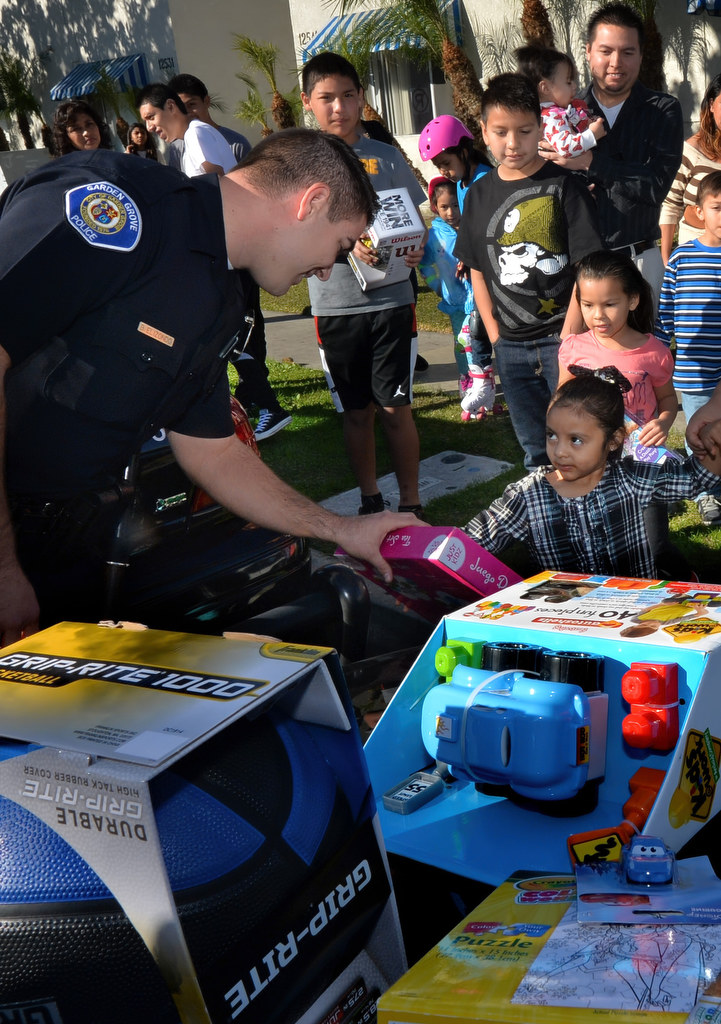 Garden Grove Officer Ben Elizondo hands out Christmas presents on Sunswept Ave. to kids who gathered at the GGPD patrol cars when they pulled up. Photo by Steven Georges/Behind the Badge OC