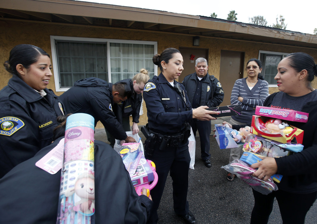 Anaheim Police Officer Leslie Vargas, center, presents Christmas gifts to families living at a local motel. The police department distributed Christmas gifts and food to needy families in the community. Photo by Christine Cotter/Behind the Badge OC