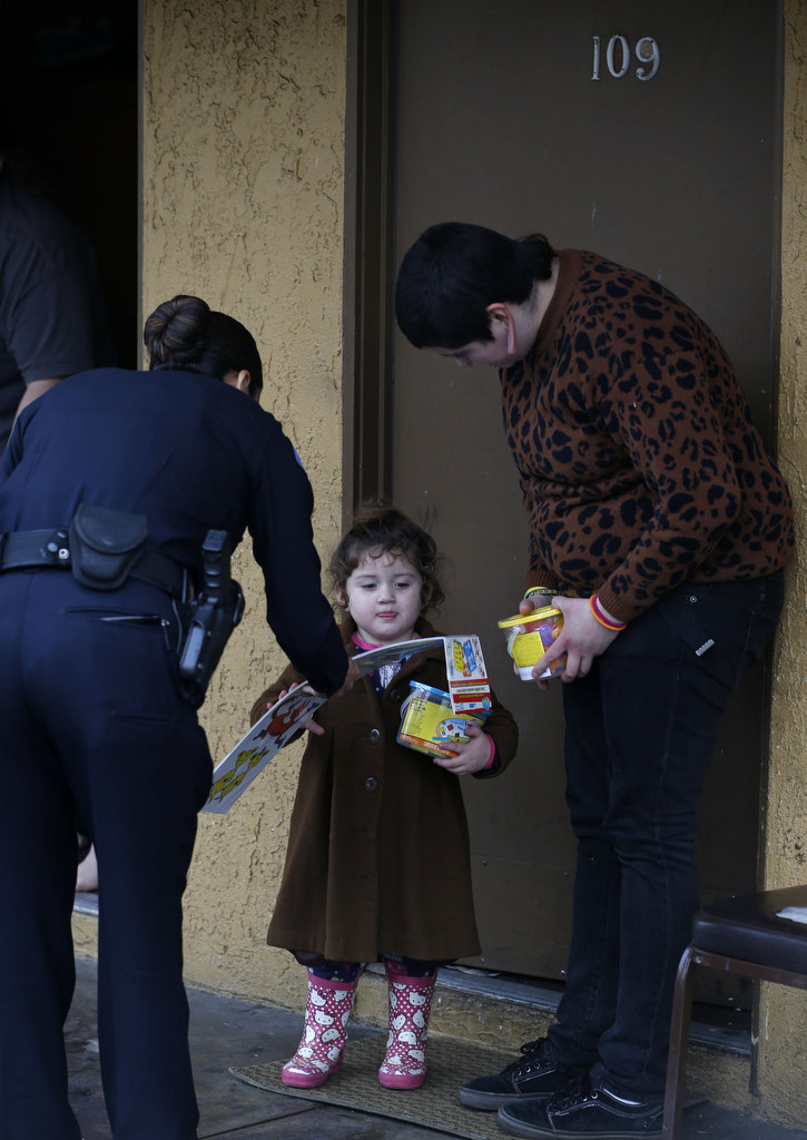 A young girl living with her family in an Anaheim motel receives Christmas gifts from the Anaheim Police department.  Photo by Christine Cotter/Behind the Badge OC