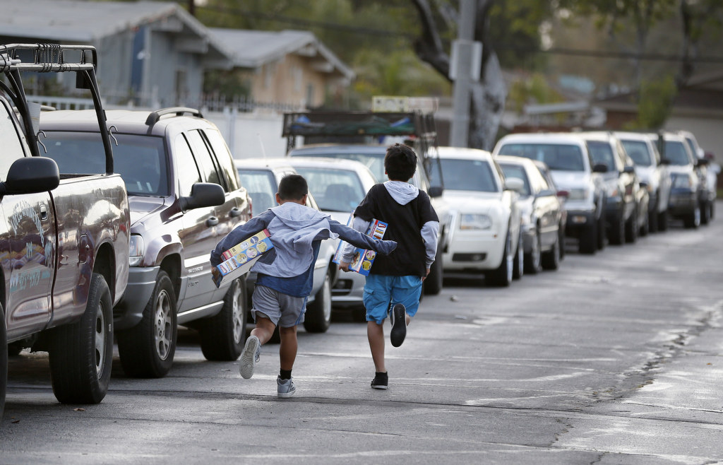 Two boys race home after receiving Christmas gifts from the Anaheim Police department. Photo by Christine Cotter/Behind the Badge OC