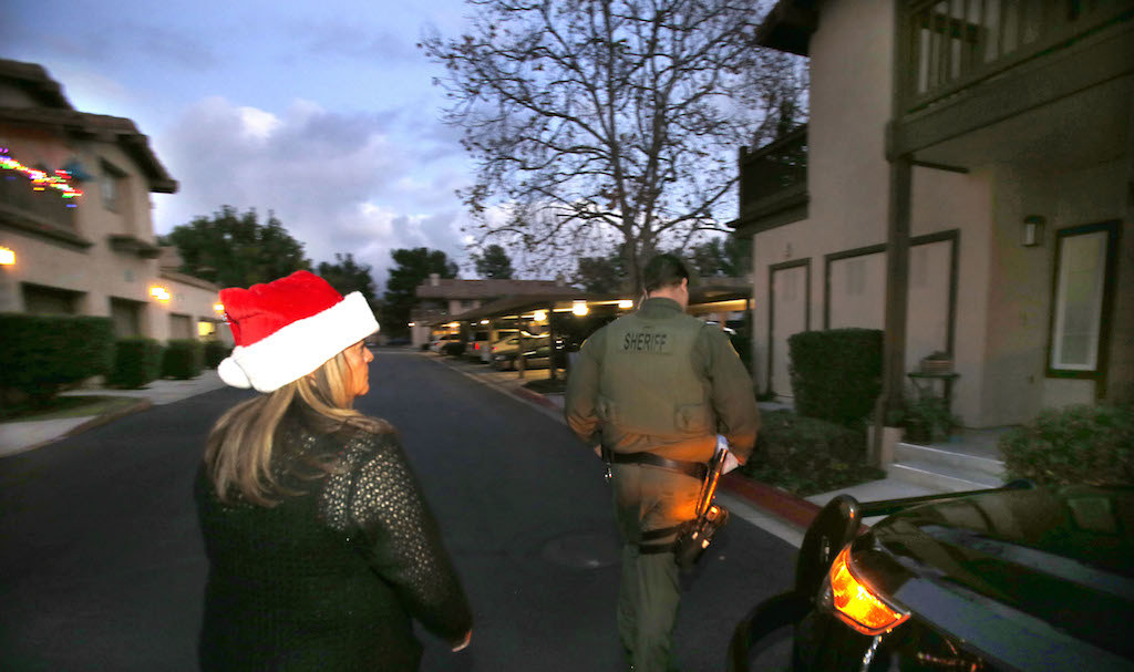 Orange County Sheriff's Robert White, right, and TIP volunteer Margie McInnis deliver a Christmas gift to a needy family in south Orange County. The Orange County Sheriff's Department is giving hundred dollar bills to help families for Christmas. Photo by Christine Cotter/Behind the Badge OC