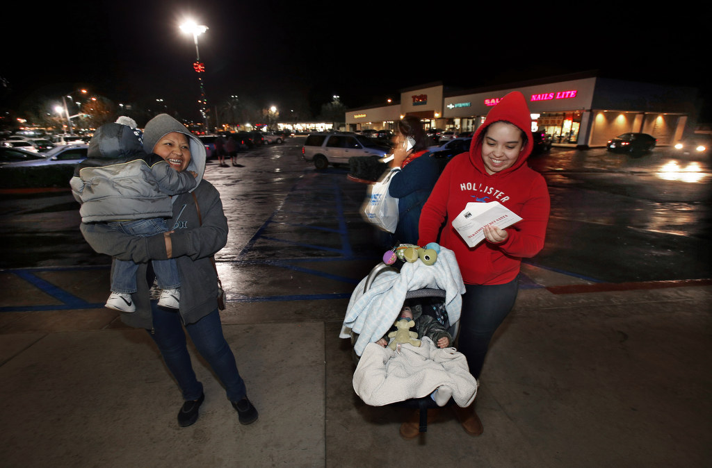 Tina Garcia, right, was a lucky recipient of a cash gift delivered by the Orange County Sheriff Department's Robert White. The sheriff's handed out hundred dollar bills to needy families during the Christmas holiday. Photo by Christine Cotter/Behind the Badge OC