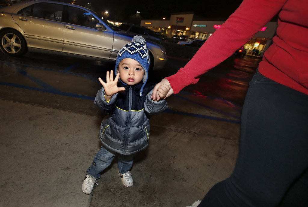 Jairo Garcia gives a wave after his mom was a lucky recipient of a cash gift from Orange County Sheriff's Deputy Ryan Miller. The Sheriff's department handed out hundred dollar bills to families in need. Photo by Christine Cotter/Behind the Badge OC