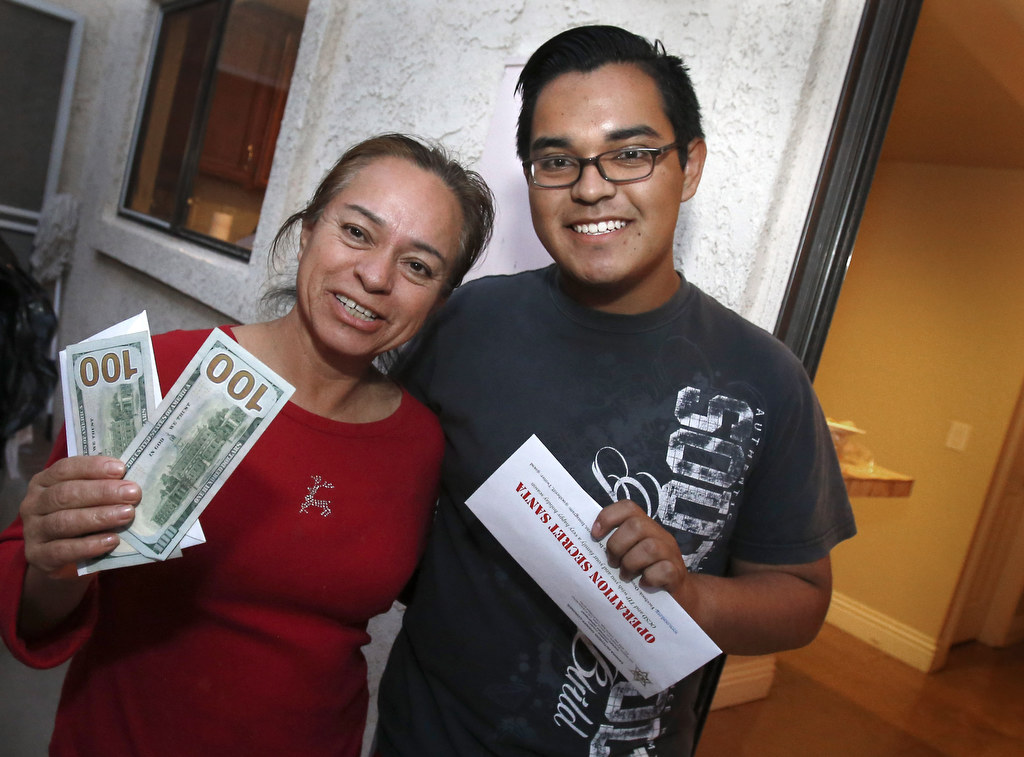 Carmela Rodriguez and her son Armando can't quite believe their good luck. They received a gift of cash delivered by the Orange County Sheriff Department.  Photo by Christine Cotter/Behind the Badge OC