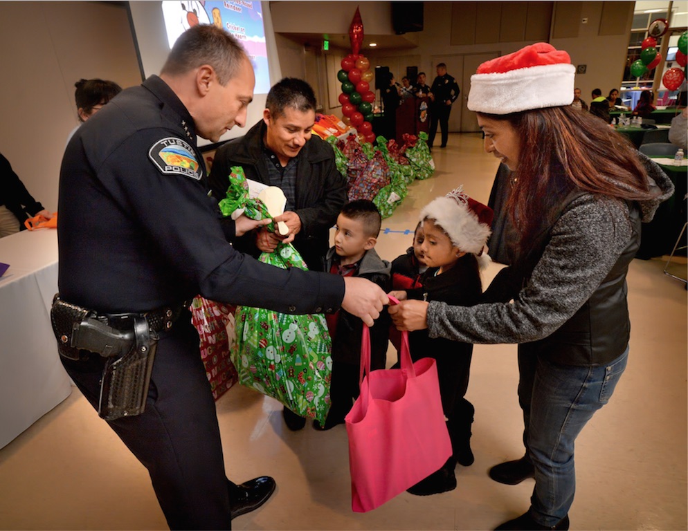 Tustin Police Chief Charles Celano presents gifts to the Mozo family as presents were handed out to each family attending Tustin PD’s annual “Santa Cop” at the Tustin Community Center. Photo by Steven Georges/Behind the Badge OC