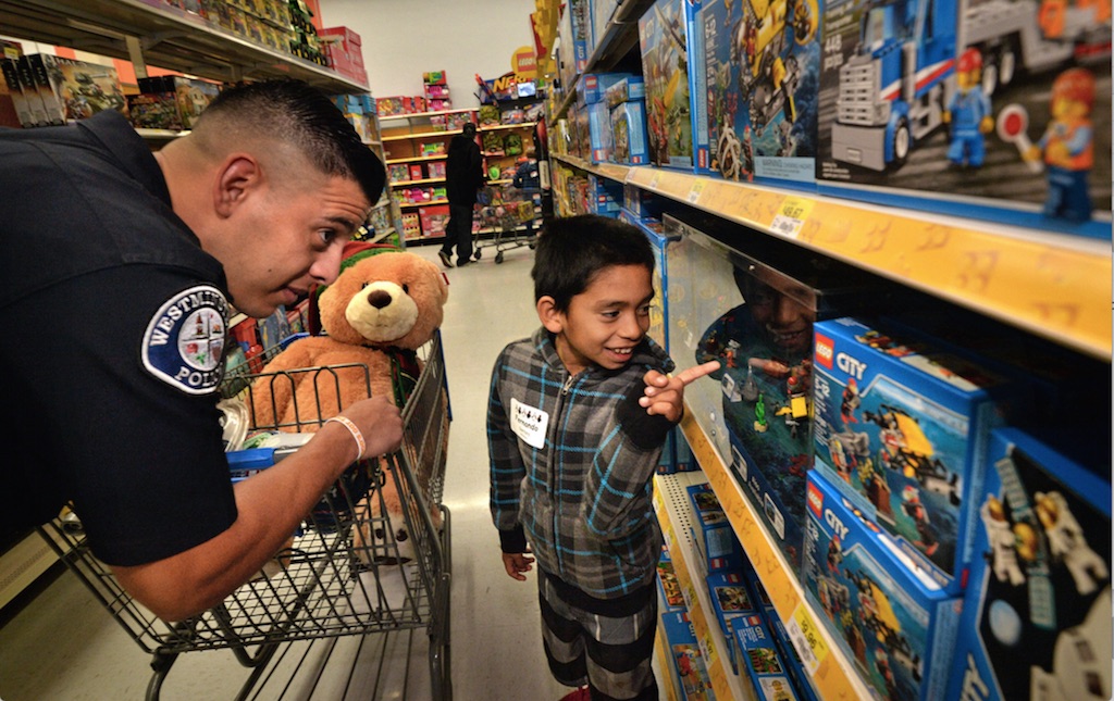 Westminster PD Officer Mike Gradilla helps Fernando Santana, 9, with a LEGO selection during Westminster PD’s annual Shop With a Cop event. Photo by Steven Georges/Behind the Badge OC