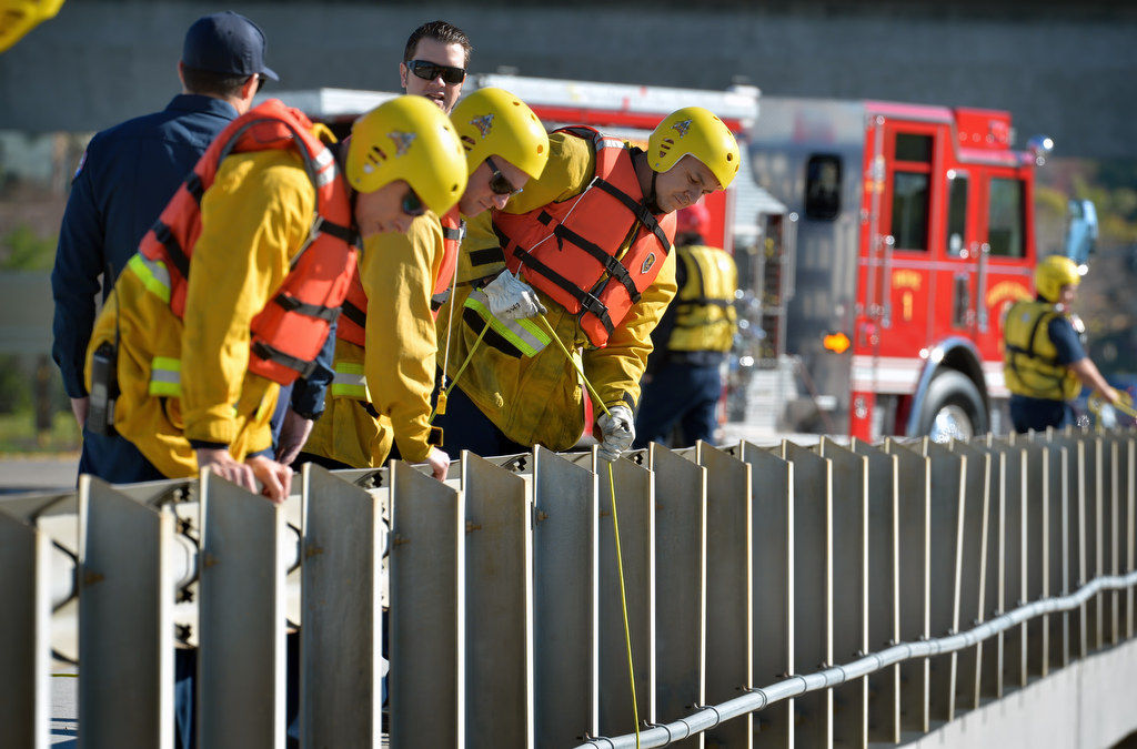 Anaheim Fire Rescue Workers lower a firehose over the side of the Orangewood Ave. bridge of the Santa Ana River to be used as a floating rescue line during a swift water rescue drill. Photo by Steven Georges/Behind the Badge OC