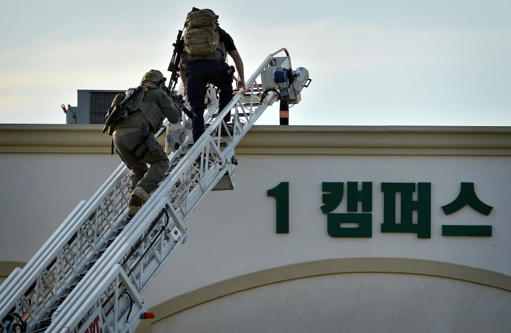 SWAT team members climb a Fullerton Fire Truck ladder to the roof of a Fullerton Presbyterian Church building in search of a suspect. Photo by Steven Georges/Behind the Badge OC