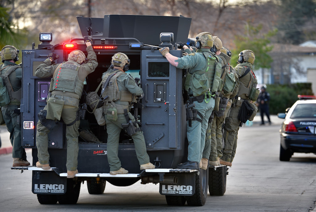 SWAT team members from Fullerton, La Habra, Placentia and La Palma police ride a SWAT truck up to a church building where a possibility armed male is held up. Photo by Steven Georges/Behind the Badge OC