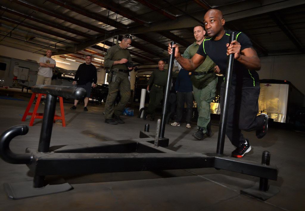 Anaheim PD Officer Sheddi Skeete pushes a weight across the workout room during a timed obstacle course. Photo by Steven Georges/Behind the Badge OC