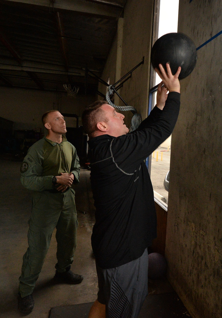 Anaheim PD Lt. Bob Dunn tosses a weighted ball above a line on the wall as part of a timed obstacle course as Officer Garrett Cross, left, follows him to each station. Photo by Steven Georges/Behind the Badge OC