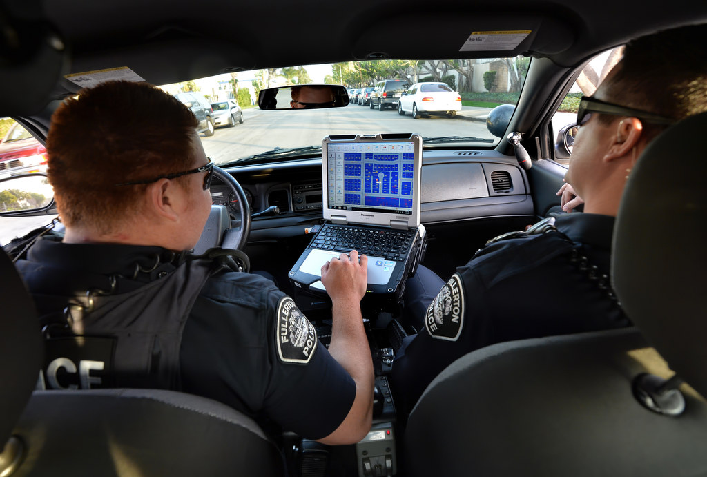 Fullerton PD Officer Jose Paez, left, and Officer Chris Murphy check the neighborhood layout on a computer map as they respond to a call. Photo by Steven Georges/Behind the Badge OC