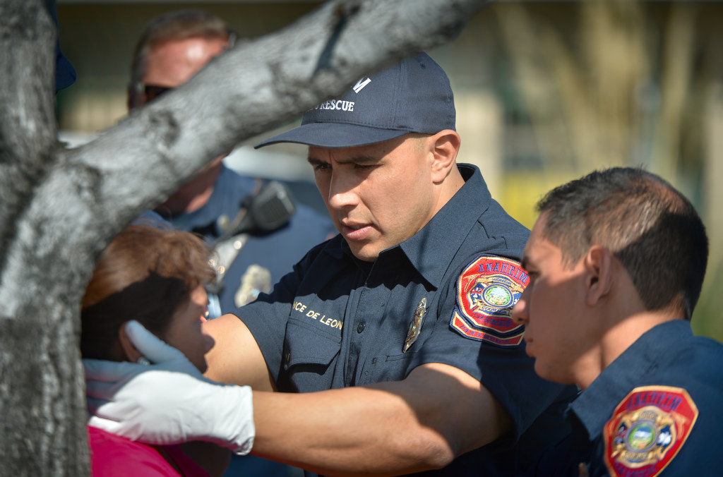 Anaheim Fire & Rescue Firefighter Paramedic Manny Ponce de Leon and Firefighter Jericho Olmedo, right, help treat a lady who was knocked down when her purse was stolen. Photo by Steven Georges/Behind the Badge OC