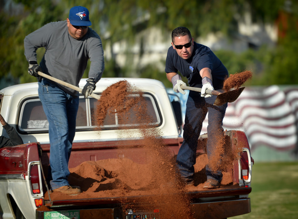 Julio Munoz, left, and Anaheim PD Officer Eric Anderson shovel fresh donated dirt onto the Little League baseball field at Sage Park as part of a renovation. Photo by Steven Georges/Behind the Badge OC