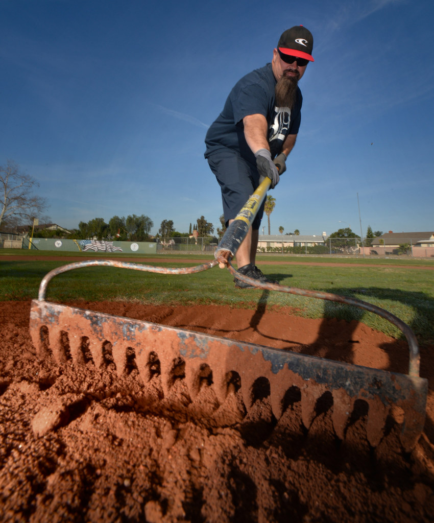Jeff Delaquil, Anaheim Little League parent and coach, rakes in new infield dirt into the pitchers mound at Sage Park. Photo by Steven Georges/Behind the Badge OC