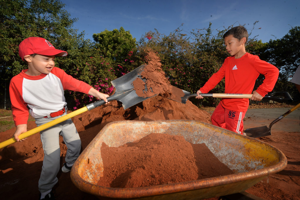 Wyatt Crawford, 7, left, and his friend Brandon Hahm, 8, load donated dirt into a wheelbarrow as volunteers renovate the Anaheim Little League field at Sage Park. Photo by Steven Georges/Behind the Badge OC