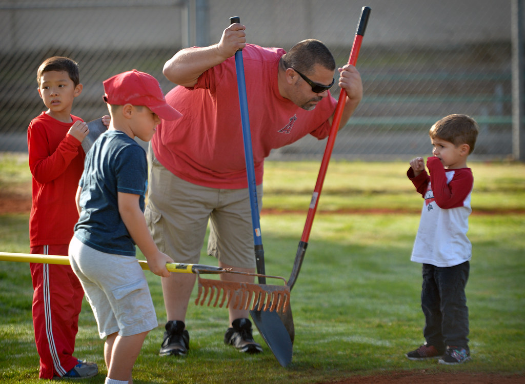 Tim Eich, Anaheim Little League parent and coach, listens to his 3-year-old son Brandon Eich, right, as volunteers volunteer to renovate the Anaheim Little League field at Sage Park. Photo by Steven Georges/Behind the Badge OC