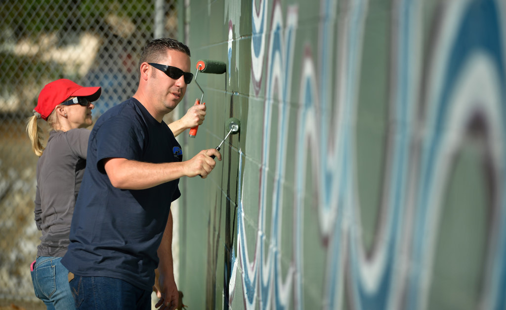Jennifer DeLaquil, Anaheim Little League parent, left, and Anaheim PD Officer Eric Anderson paint over the La Palma Little League wall with a fresh coat of paint. The West Anaheim Little League and La Palma Little League recently merged to form the new Anaheim Little League. Photo by Steven Georges/Behind the Badge OC
